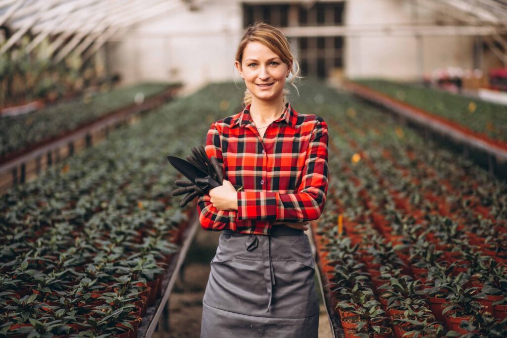 Woman gardner looking after plants in a greenhouse